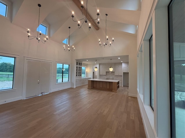 15420 Highlander Ct, Montgomery, TX 77356 - unfurnished living room with a chandelier, high vaulted ceiling, beamed ceiling, light wood finished floors, and baseboards