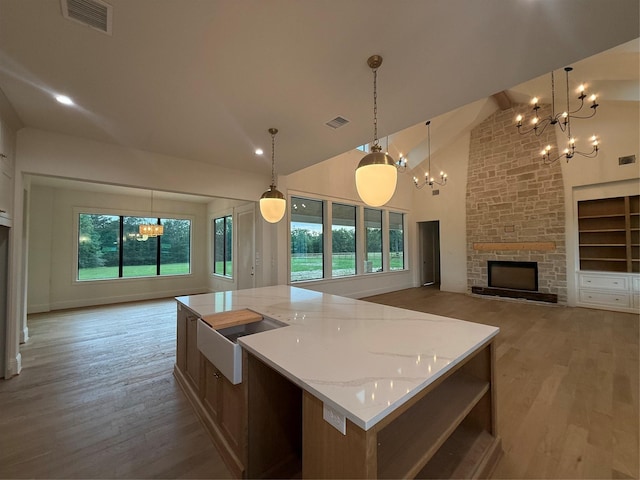 15420 Highlander Ct, Montgomery, TX 77356 - kitchen featuring a chandelier, a fireplace, light wood-style floors, high vaulted ceiling, and a spacious island
