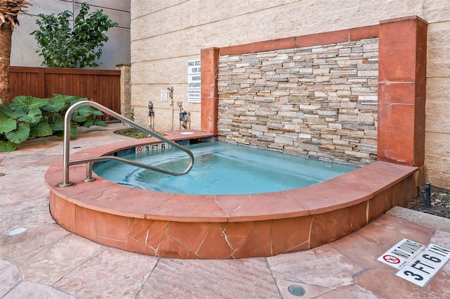 view of swimming pool featuring a community hot tub and fence