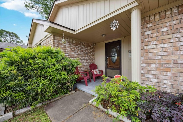 view of exterior entry with brick siding and covered porch