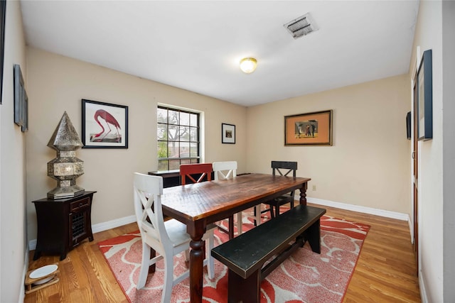 dining space with baseboards, visible vents, and light wood-style flooring
