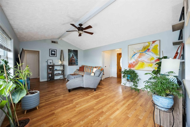 living room with visible vents, lofted ceiling with beams, light wood-style flooring, a textured ceiling, and ceiling fan