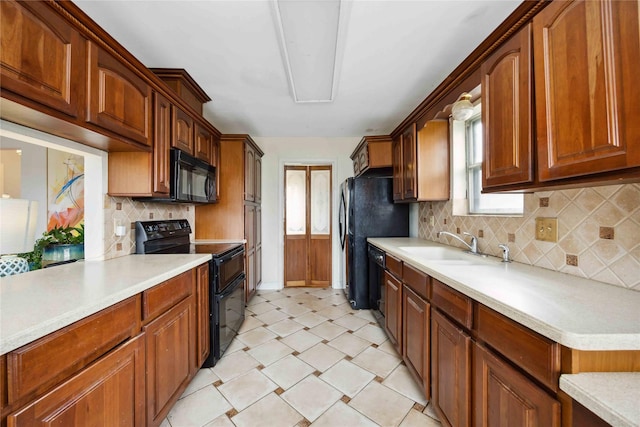 kitchen featuring a sink, black appliances, light floors, light countertops, and backsplash