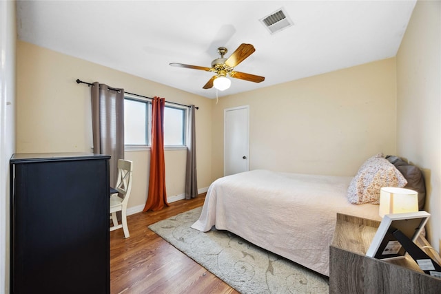 bedroom featuring wood finished floors, visible vents, a ceiling fan, and baseboards