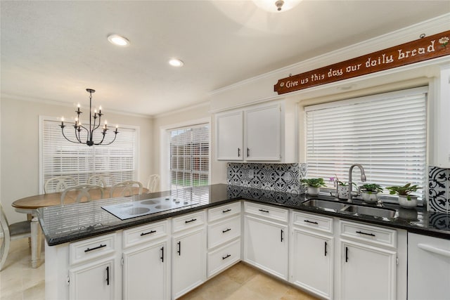 2104 Olympic Dr, League City, TX 77573 - kitchen with a peninsula, a sink, a chandelier, white cabinetry, and crown molding