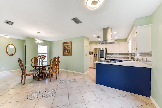 kitchen featuring tasteful backsplash, a sink, island range hood, appliances with stainless steel finishes, and white cabinetry