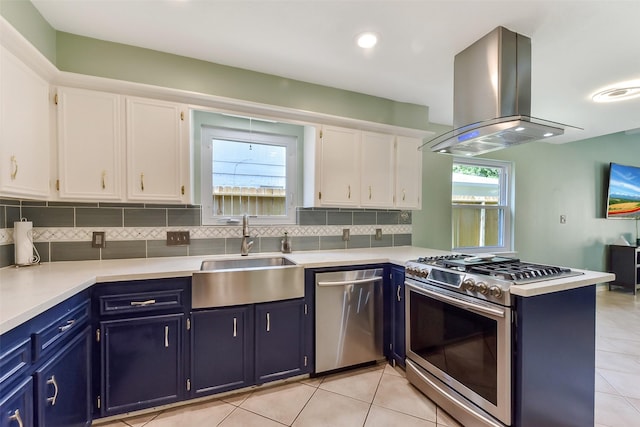 kitchen with white cabinets, island range hood, blue cabinets, a sink, and appliances with stainless steel finishes