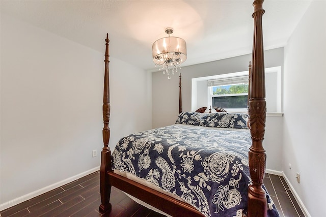bedroom with wood finished floors, baseboards, and a notable chandelier