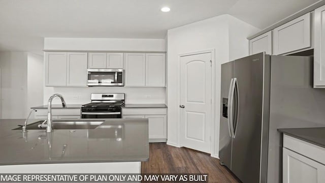 kitchen featuring recessed lighting, stainless steel appliances, dark countertops, a sink, and dark wood-type flooring