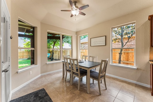 dining area with a textured wall, a ceiling fan, baseboards, and light tile patterned floors
