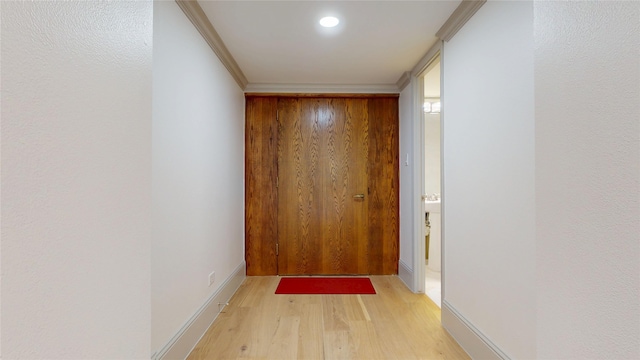 hall with baseboards, light wood-style floors, and ornamental molding