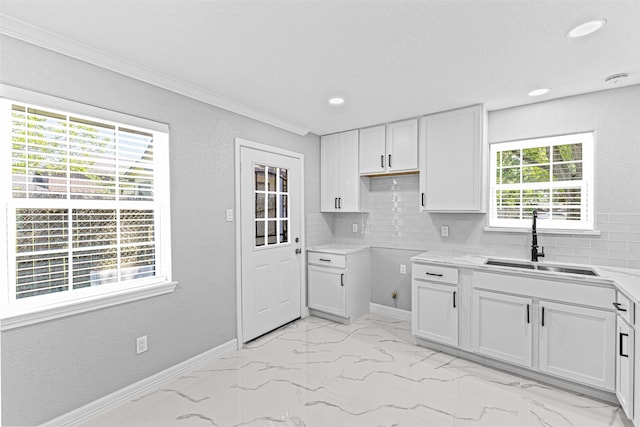 kitchen featuring white cabinets, marble finish floor, a sink, baseboards, and tasteful backsplash