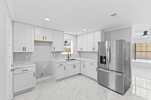 kitchen featuring marble finish floor, a sink, white cabinets, and stainless steel fridge