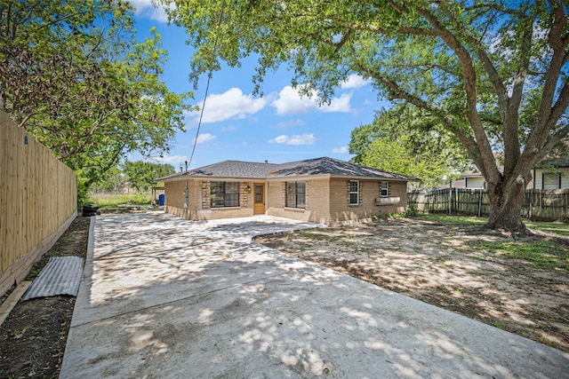 view of front facade with fence, driveway, and brick siding