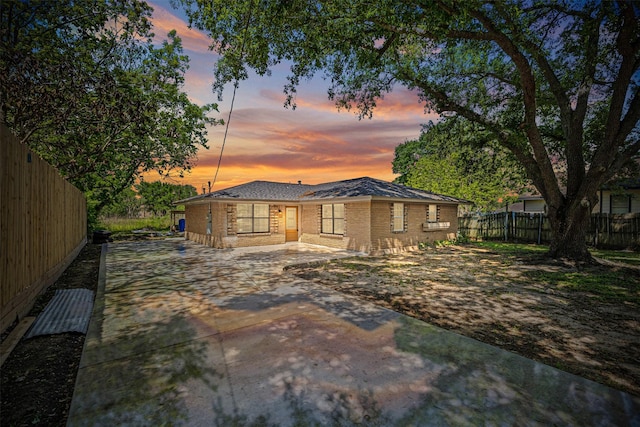 back of property with brick siding, fence, and driveway