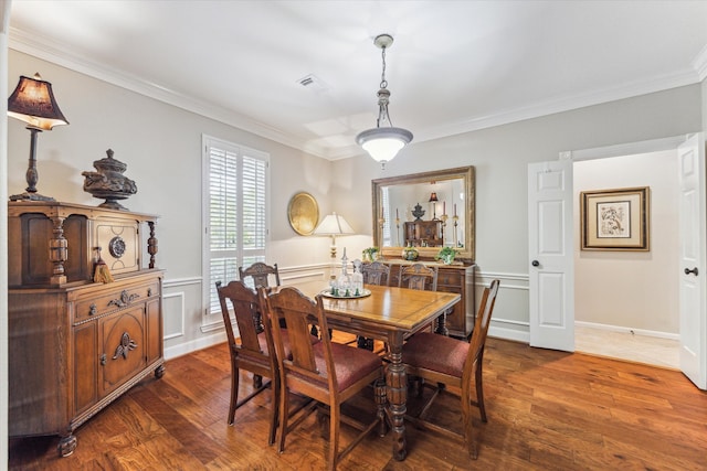 dining area with dark wood finished floors, visible vents, a wainscoted wall, and ornamental molding