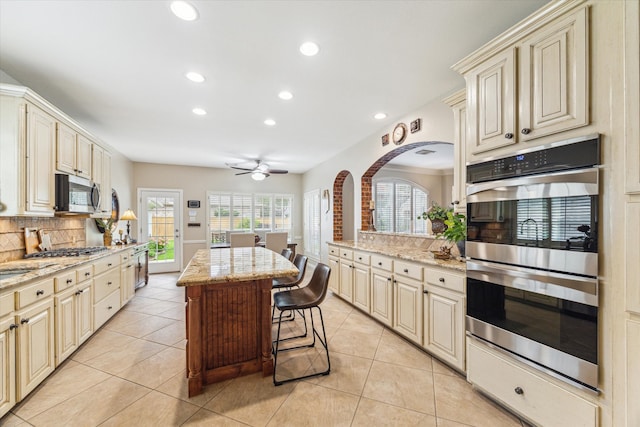 kitchen featuring tasteful backsplash, cream cabinets, and stainless steel appliances