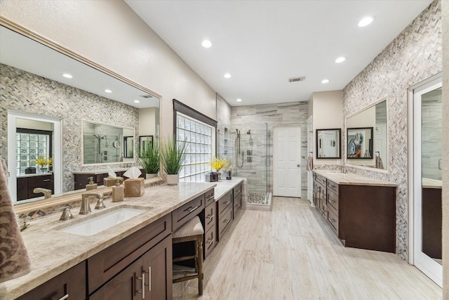 bathroom with recessed lighting, a shower stall, a wealth of natural light, and a sink
