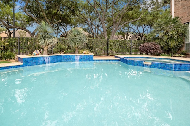 view of swimming pool featuring fence and a pool with connected hot tub