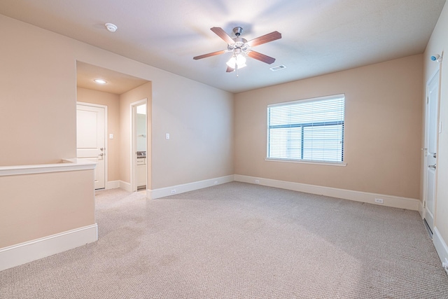 empty room featuring light carpet, a ceiling fan, visible vents, and baseboards