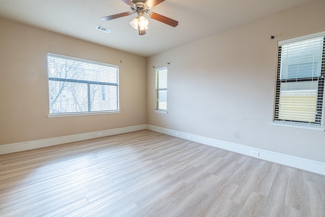 spare room featuring wood finished floors, visible vents, a ceiling fan, and baseboards