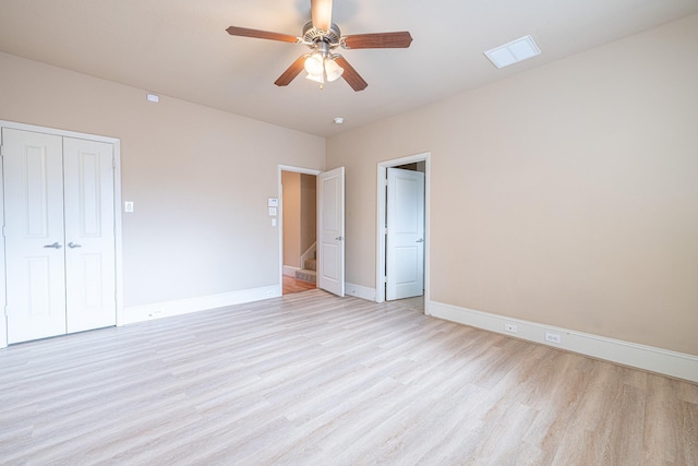 unfurnished bedroom featuring light wood-type flooring, baseboards, visible vents, a ceiling fan, and a closet