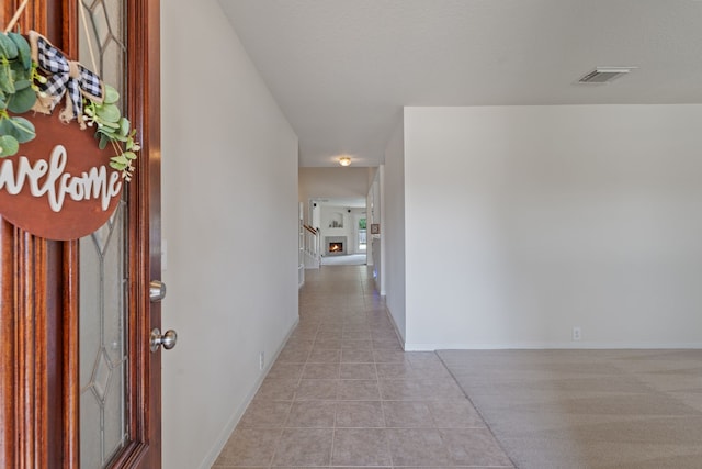 hallway featuring visible vents, baseboards, and light tile patterned floors