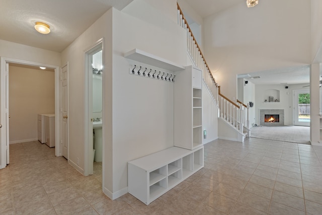 mudroom with a tile fireplace, baseboards, light tile patterned floors, and washer / clothes dryer