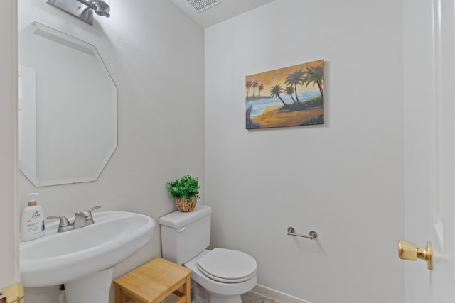 bathroom with visible vents, toilet, baseboards, and a sink