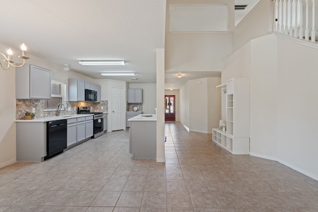 kitchen with a sink, black appliances, decorative backsplash, light tile patterned floors, and light countertops