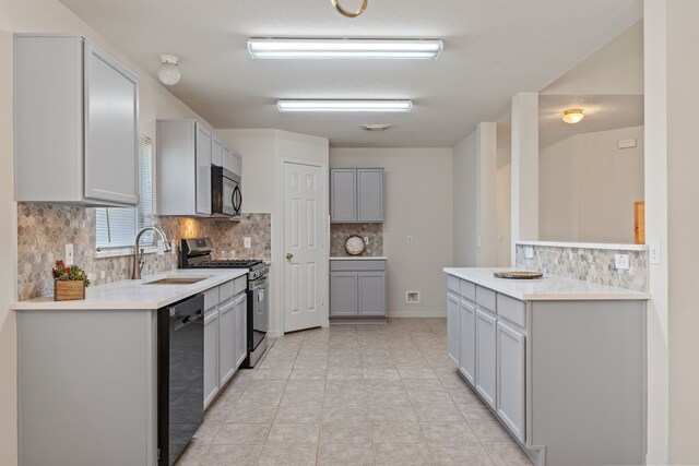 kitchen with a sink, tasteful backsplash, gray cabinets, light countertops, and black appliances
