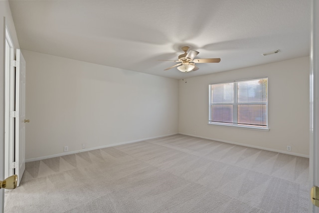 spare room with ceiling fan, visible vents, baseboards, and light carpet