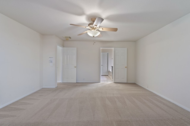 spare room featuring light colored carpet, ceiling fan, baseboards, and visible vents