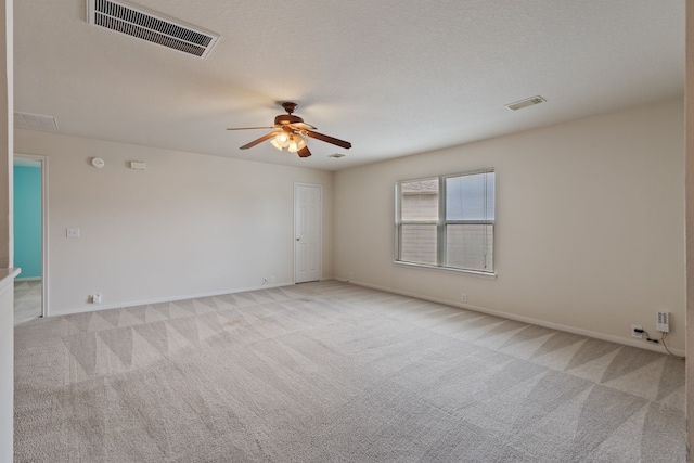 empty room with light carpet, a ceiling fan, visible vents, and baseboards