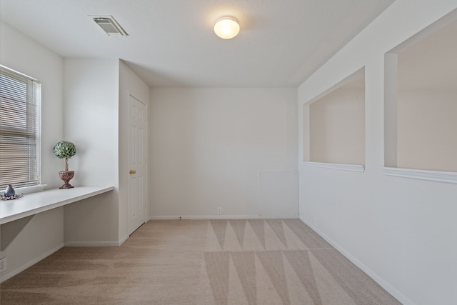 unfurnished room with light carpet, visible vents, and baseboards