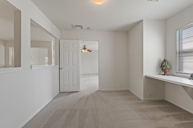 carpeted empty room with baseboards, a ceiling fan, and visible vents