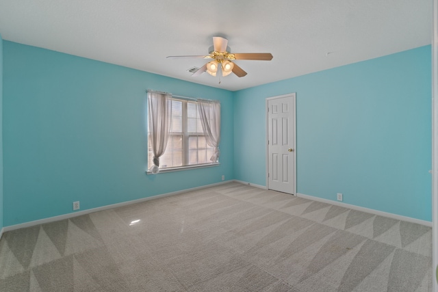 spare room featuring carpet floors, visible vents, baseboards, and ceiling fan