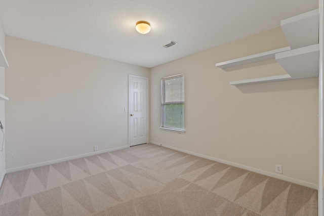 spare room with light colored carpet, baseboards, and visible vents