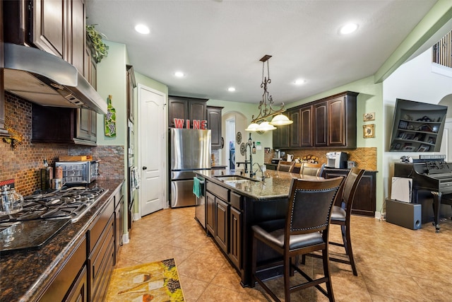 kitchen with arched walkways, a sink, dark stone counters, extractor fan, and decorative backsplash