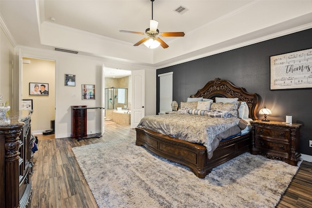 bedroom featuring wood finished floors, a tray ceiling, and visible vents