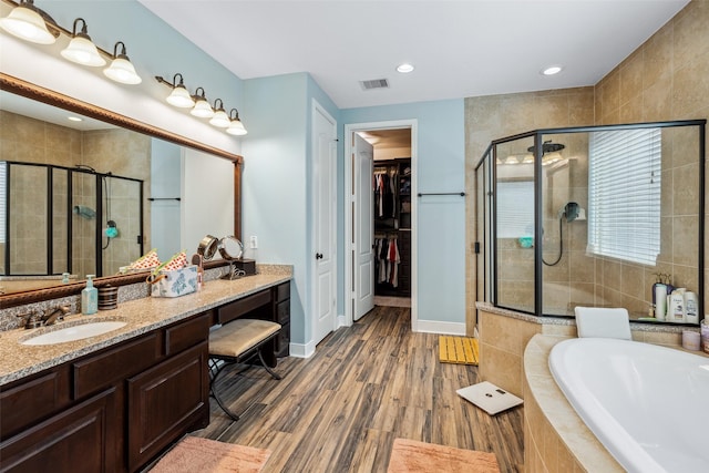 full bath with a shower stall, a garden tub, wood finished floors, and visible vents