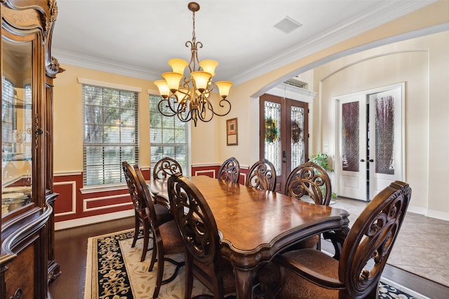 dining room featuring arched walkways, a notable chandelier, french doors, and crown molding