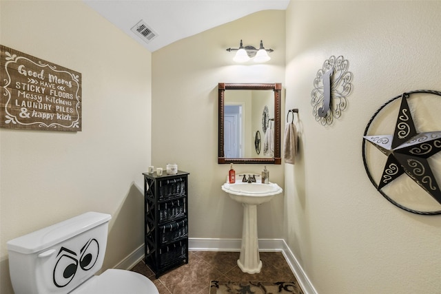 bathroom featuring toilet, vaulted ceiling, baseboards, visible vents, and tile patterned flooring
