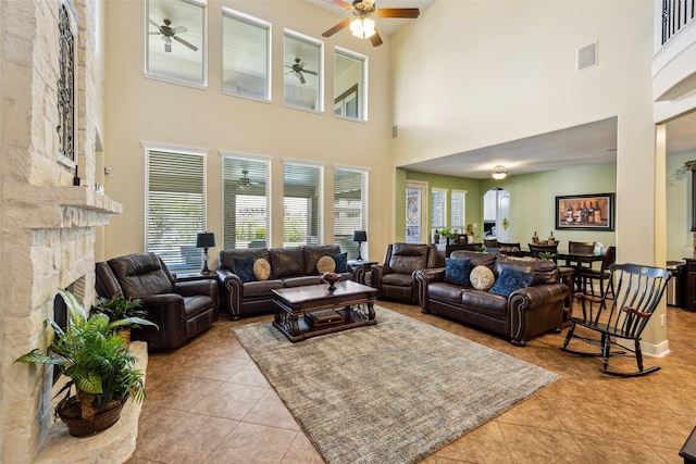 living room with tile patterned floors, a ceiling fan, a towering ceiling, and a wealth of natural light