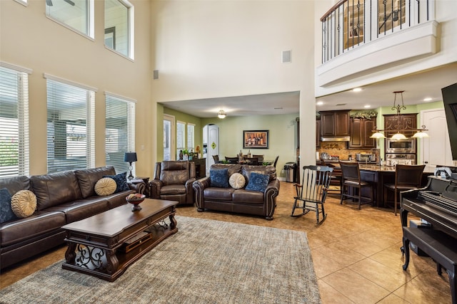 living room featuring light tile patterned flooring, a towering ceiling, and visible vents