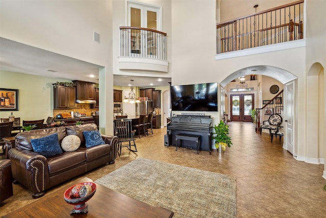living area with a high ceiling, arched walkways, visible vents, and light tile patterned floors