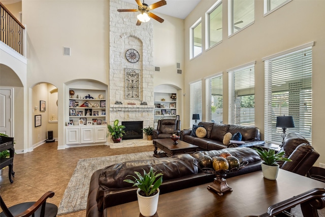 tiled living area featuring baseboards, a towering ceiling, built in features, and ceiling fan