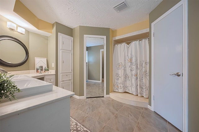 bathroom with a textured ceiling, a shower with curtain, vanity, tile patterned flooring, and baseboards