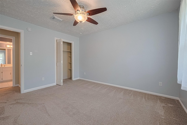 unfurnished bedroom featuring a textured ceiling, light colored carpet, baseboards, a closet, and ceiling fan