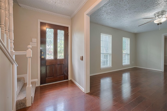 foyer with a textured ceiling, dark wood-type flooring, a ceiling fan, stairs, and baseboards